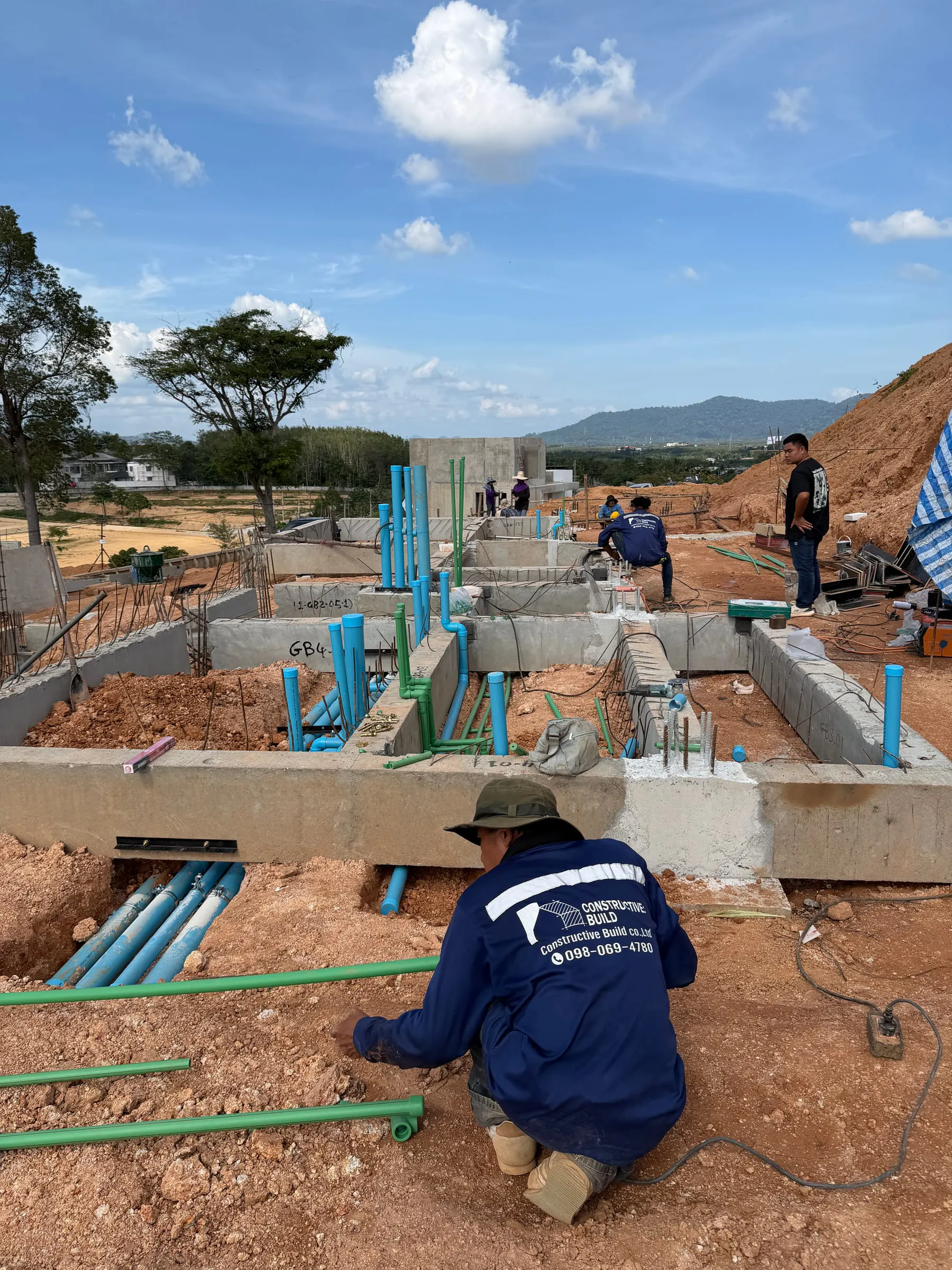 C:B crew on MEP first-fix at the KAHLI hillside site, mountains in background