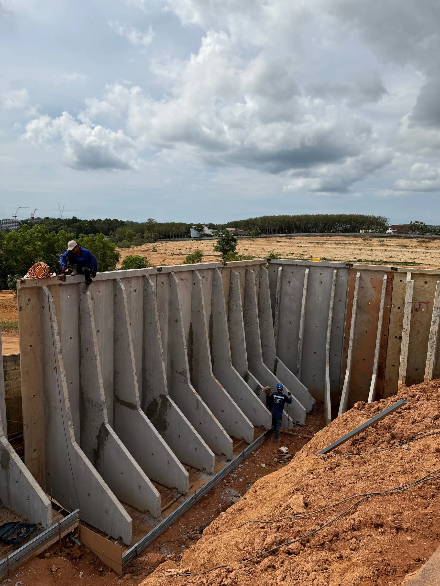 Completed precast retaining wall at full height, workers on top